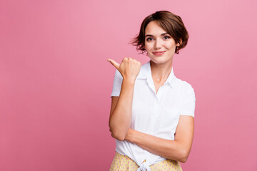 Wall Mural - Photo of overjoyed woman with bob hairdo dressed white shirt directing look at promo empty space isolated on pink color background