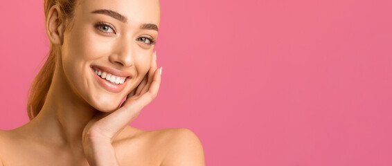 Wall Mural - A close-up portrait of a young woman with fair skin and red hair, looking directly at the camera with a bright smile, showing her white teeth, panorama with copy space