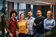 © .shock - Portrait of successful creative business team looking at camera and smiling. Diverse business people standing together at startup. Selective focus