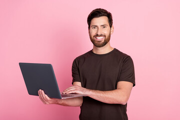 Wall Mural - Portrait of optimistic positive man with stylish bristle wear brown shirt holding laptop read email isolated on pink color background