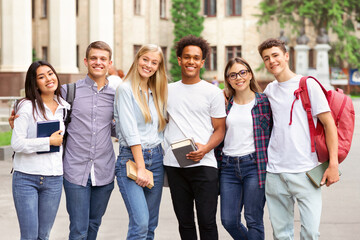 Wall Mural - Diverse students in campus, posing in front of university and looking at camera