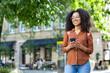 © Tetiana - Smiling woman tourist walking in city on vacation using smartphone
