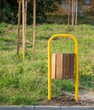 © Todor - Yellow metal and wood trash can in a park with green grass