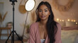 © Andres Mejia - Young influencer woman recording video blog sitting on bedroom floor using camera