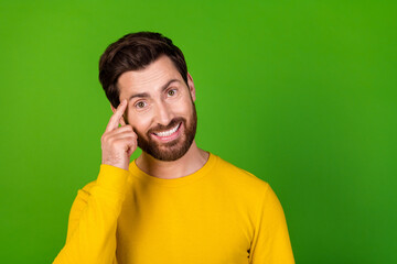 Photo of clever man with stylish beard dressed yellow shirt hold finger on eyebrow have great idea isolated on green color background