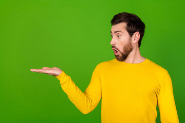 Photo portrait of handsome young guy hold look amazed empty space dressed stylish yellow garment isolated on green color background