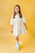 © Melissa Milis Photography/Stocksy - Kid modeling soft yellow dress in studio