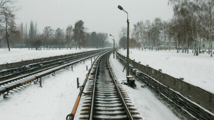 Railway in the winter. High-speed train goes in the winter season. Snow flies in the window of the driver. Long track.