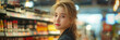 © S photographer - Asian female customer holding wine bottle in hand at supermarket store.