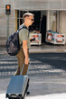 © Ivan Haidutski/Stocksy - man with backpack hold phone, carrying baggage cross pedestrian walk