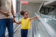 © Jovo Jovanovic/Stocksy - Girl holding hand of father on moving walkway in mall