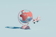 © Giada Canu/Stocksy - Coral Globe with Toy Airplane on Light Blue Background