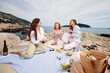 © Boris Jovanovic/Stocksy - Women are picnicking on the rocks by the sea