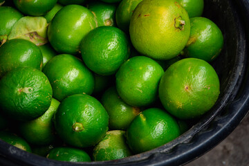 A bunch of green limes in a black bowl