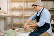© Artem Podrez/Stocksy - Focused Craftsman at Work on Pottery Wheel