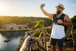 © Daniel Gonzalez/Stocksy - Man Taking Selfie by Scenic Coast