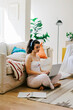© BONNINSTUDIO/Stocksy - Woman enjoying cozy home time with laptop