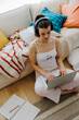 © BONNINSTUDIO/Stocksy - Woman enjoying music while working on laptop at home