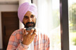 © Wavebreak Media - Speaking into smartphone, Indian man in turban standing by window at home