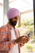 © Wavebreak Media - Using smartphone, man in turban standing by window at home