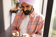 © Wavebreak Media - Using smartphone, man in turban texting and browsing at home