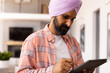 © Wavebreak Media - Using tablet, man in turban focusing on work at home