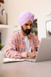 © Wavebreak Media - Using laptop, man in turban working from home with notepad on table
