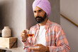 © Wavebreak Media - Holding cup of tea, man in turban standing at home, looking thoughtful