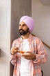 © Wavebreak Media - Holding cup of tea, man in turban standing and looking away