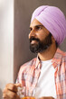 © Wavebreak Media - Smiling man in turban holding cup of tea, enjoying peaceful moment at home