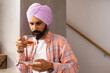 © Wavebreak Media - Drinking tea, man in turban reading on smartphone at home