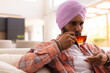 © Wavebreak Media - Drinking tea, man in turban relaxing on couch at home