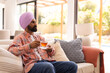 © Wavebreak Media - Relaxing on sofa, man in turban drinking tea in cozy living room