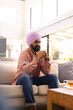 © Wavebreak Media - Sitting on couch, man with turban drinking tea and relaxing at home