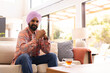 © Wavebreak Media - Sitting on sofa, man with turban relaxing at home with cup of tea, copy space