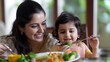 © Natalia S. - Indian Mother and daughter enjoying food together. A healthy dish with vegetables, including broccoli