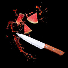 Wall Mural - sliced watermelon with watermelon juice splash and knife on black background,stop motion