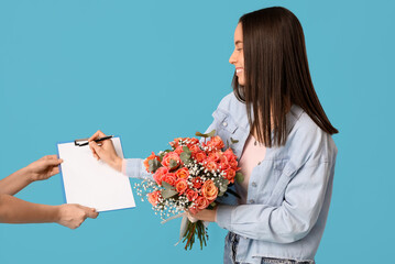 Wall Mural - Young woman receiving bouquet of beautiful flowers on blue background