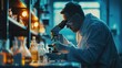 © itchaznong - A scientist is looking through a microscope at a sample