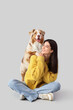 © Pixel-Shot - Young woman with Australian Shepherd dog sitting on light background