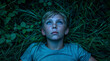 © Rajko - Young boy laying in grass t night looking up at sky