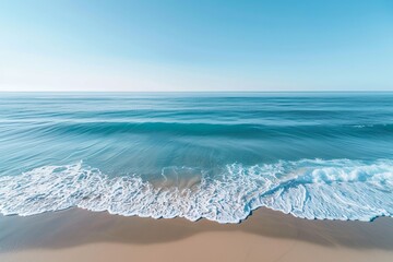 A high-angle shot capturing the calming rhythm of ocean waves gently rolling onto a sandy beach