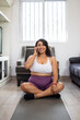 © cesar - Overweight brunette latin woman making phone call, while doing yoga sitting on mat