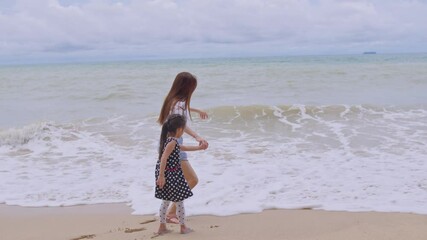 Wall Mural - Asian beautiful mother walking with adorable daughter on the beach. 