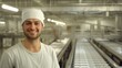 © Dmitriy - smiling production worker in casual attire, working in a clean, modern production hall. In the background, conveyor belts are visible, assembling battery packs for electric vehicles