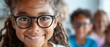 © Ruby Siam - Smiling girl wearing glasses looks at the camera with her classmates in the background.