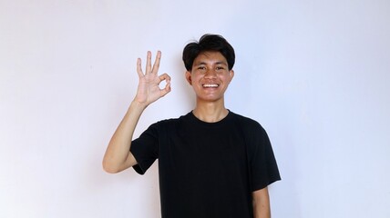 Excited young Asian man wearing black shirt gesturing okay with hand. copy space, success, happiness, say yes, okay, good, delicious