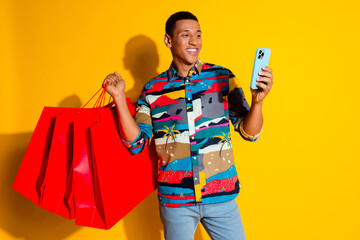 Wall Mural - Photo portrait of nice young male shopping bags hold device dressed stylish colorful garment isolated on yellow color background