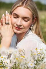 Wall Mural - Portrait of a young beautiful blonde in a chamomile field