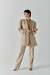 © LIGHTFIELD STUDIOS - Stylish woman in beige suit poses confidently against white backdrop.